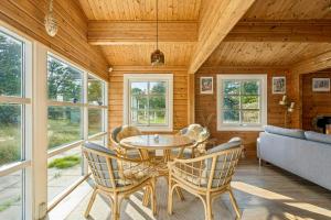 een eetkamer met een tafel, stoelen en ramen bij Timber House On Dune Plot Near Hulsig in Hulsig