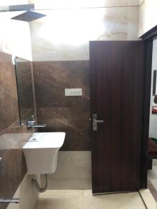 ein Badezimmer mit Waschbecken und Holztür in der Unterkunft Hotel Bharat Residency in Amritsar + 5 Fotos
