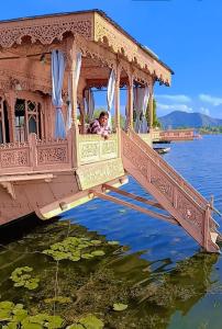 a woman is looking out from a house on a bridge in the water at Maharaja palace houseboat in Srinagar