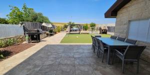 a patio with a table and chairs and a lawn at נווה שחר- צימר משפחתי מקסים עם ג'קוזי פרטי ובריכה ליד הכנרת in Poriyya Illit