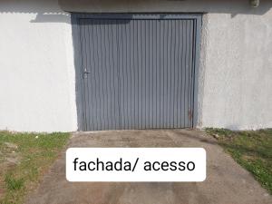 une porte de garage avec un panneau indiquant « faciada assos » dans l'établissement Kitnet geminada próximo da praia, à Torres