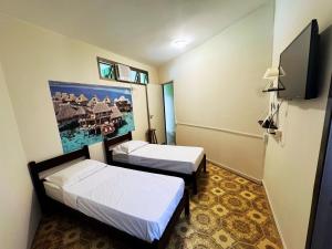 Una habitación con dos camas y un televisor de pantalla plana. en Tombo Beach Yoga Bem-estar, en Guarujá