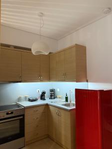 cocina con armarios de madera y nevera roja en Achinoeè, en Chalkida
