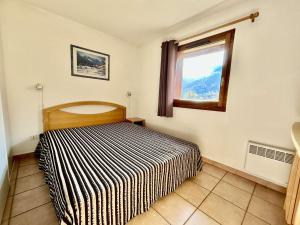 a bedroom with a bed with a striped blanket at Appartement cosy 3 pièces pour 6 pers. - Serre Chevalier - FR-1-330F-26 in Serre Chevalier