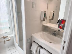 ein weißes Badezimmer mit Waschbecken und Spiegel in der Unterkunft Hôtel des Voyageurs in Saint-Chély-dʼAubrac + 18 Fotos