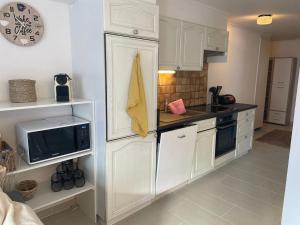 une cuisine avec des armoires blanches et un micro-ondes dans l'établissement Centrally located and comfortable apartment - Daubenhorn 32, à Arni Alp 10 autres photos