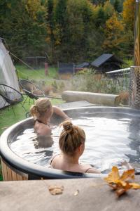 zwei Mädchen in einem Whirlpool im Garten in der Unterkunft Domek Pierwiosnek Ustroń - cisza, las, balia i totalny relaks - Ucieknij od zgiełku i poczuj spokój natury in Ustroń