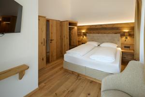 a bedroom with a white bed and a chair at Die Monika Aparthotel in Gaschurn