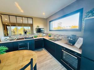 a kitchen with blue cabinets and a table and a window at Villa Palmiers 5 min de la Mer, confortable 4 Personnes, parking free, in Sérignan