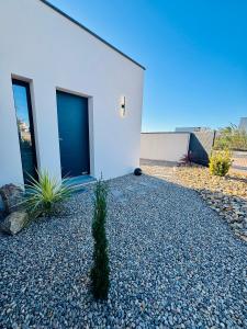 a white building with a blue door on the side of it at Villa Palmiers 5 min de la Mer, confortable 4 Personnes, parking free, in Sérignan