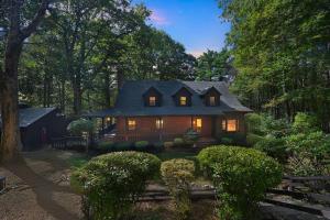 ein Haus im Wald mit eingeschaltetem Licht in der Unterkunft Cushing Home - Family Cabin Near Wachusett Mtn home in Ashburnham