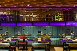 un restaurante con mesas, sillas e iluminación púrpura en NYX Hotel Edinburgh, en Edimburgo