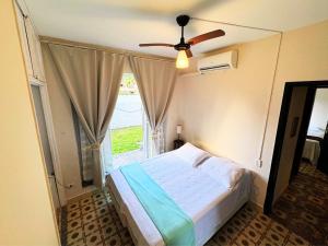 Un dormitorio con una cama y un ventilador de techo. en Tombo Beach Yoga Bem-estar, en Guarujá