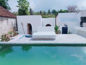 una piscina con 2 sillas blancas junto a una casa en Dragonfly, en Nusa Penida