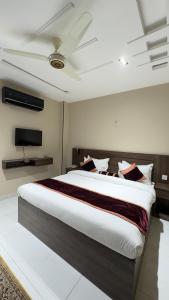 une chambre avec un grand lit et une télévision à écran plat dans l'établissement Marigold hotel and restaurant, à Sialkot