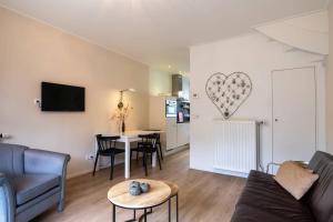 a living room with a couch and a table with a heart on the wall at Hello Zeeland - JW Schuurmanstraat 116 in Domburg
