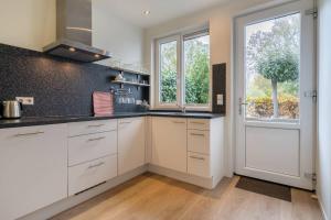 a kitchen with white cabinets and a large window at Hello Zeeland - JW Schuurmanstraat 116 in Domburg