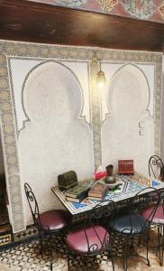 a table with chairs and books on it in a room at Riad BAB JDID in Fès