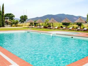 une grande piscine bleue avec chaises et parasols dans l'établissement Residence Cernaia - Private Cottage, à Castiglione della Pescaia