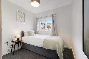 ein weißes Schlafzimmer mit einem Bett und einem Fenster in der Unterkunft Durham WorkNest in Burnhope