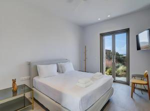 une chambre blanche avec un grand lit et une fenêtre dans l'établissement Overture House Antiparos, à Andiparos