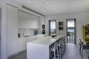 une cuisine avec des placards blancs et un grand îlot blanc dans l'établissement Overture House Antiparos, à Andiparos