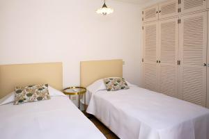 two beds in a small room with white walls at Casa do Poço in Faro