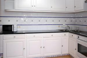 a white kitchen with white cabinets and a microwave at Casa do Poço in Faro +7 photos