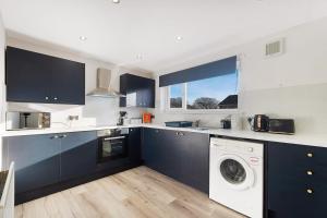 eine Küche mit blauen Schränken und einer Waschmaschine und einem Trockner in der Unterkunft Durham WorkNest in Burnhope