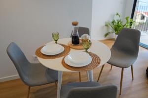 a white table with four chairs and a bottle of wine at Vivenda Silva in Seixal