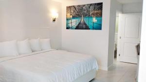 ein weißes Schlafzimmer mit einem Bett und einem Bild an der Wand in der Unterkunft Palm Breeze Hotel in Lake Worth + 49 Fotos