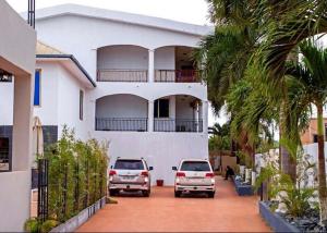 two cars parked in front of a white house at Hotel Spintex and tours in Accra