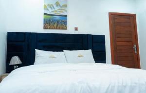 a bedroom with a large white bed with a blue headboard at Hotel Spintex and tours in Accra