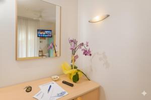 einen Schreibtisch mit einer Vase aus Blumen und einem Spiegel in der Unterkunft Hotel Ferrara in Cattolica