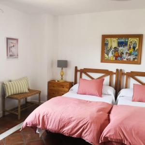 a bedroom with two beds with pink sheets and a chair at villa el almendro in Carratraca +57 photos