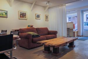 uma sala de estar com um sofá castanho e uma mesa de madeira em Galerie Nakai Art B&B em Tournus