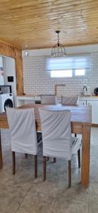 a kitchen with a wooden table and white chairs at La casita in Zapala