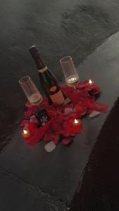 a bottle and two wine glasses and candles on the ground at tour des étoiles love room in Trévoux