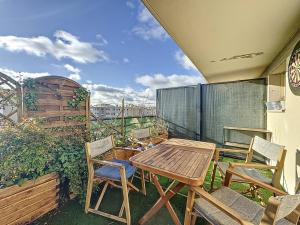 eine Terrasse mit einem Holztisch und Stühlen auf dem Balkon in der Unterkunft Duplex Prestige 5p RER Paris 15 min in Joinville-le-Pont