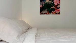 a white bed with a pillow and a picture on the wall at Temporario Sur, hasta 4 personas con 3 camas, General Roca in General Roca