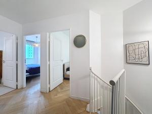 einen Flur mit weißen Wänden und eine Treppe mit Spiegel in der Unterkunft Duplex Prestige 5p RER Paris 15 min in Joinville-le-Pont