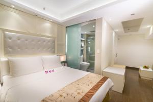 a bedroom with a large white bed and a bathroom at Empress Hotel Ho Chi Minh City in Ho Chi Minh City