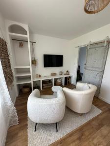 a living room with two white chairs and a television at La Casita in Maisoncelles-du-Maine +5 photos