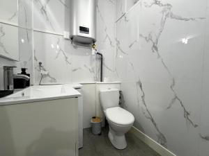 a white bathroom with a toilet and a sink at Appartement neuf 4 prsn Au cœur du Centre Ville in Besançon