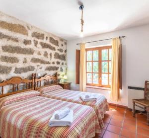 a bedroom with two beds and a stone wall at La Bodega de Gredos in Navaluenga