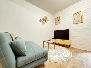 a living room with a couch and a flat screen tv at Appartement neuf 4 prsn Au cœur du Centre Ville in Besançon