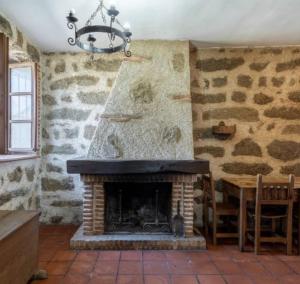 a fireplace in a room with a table and a chandelier at La Bodega de Gredos in Navaluenga