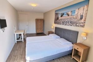 une chambre avec un grand lit blanc et un bureau dans l'établissement Hello Zeeland - Wijngaardstraat 29, à Domburg