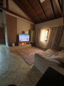 ein Wohnzimmer mit einem Bett und einem Flachbildfernseher in der Unterkunft Casa em Pedra Azul in Pedra Azul