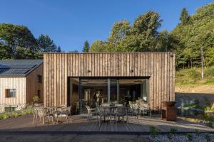 - un bâtiment en bois avec des tables et des chaises sur une terrasse dans l'établissement Apartmány Hraničná s privátním wellness, à Bedřichov
